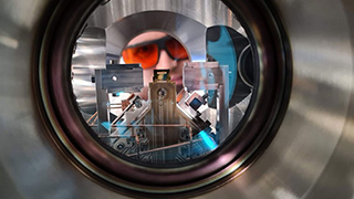 A researcher looks into the ultra-high vacuum chamber of a trapped-ion quantum computer at PSI. Soon, quantum computers at the ETHZ-PSI Quantum Computing Hub will also be used to perform quantum simulations. (© Paul Scherrer Institute/Edgar Brucke)