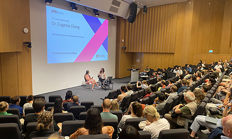 Audience watching the discussion with Eugenia Cheng in a big lecture hall.