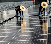 Two people with big straw hats working on a solar panel