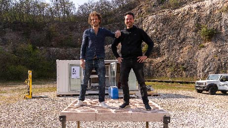 Researchers Pietro and Francesco on the printed slab on site in the Ticino quarry in front of the mobile 3D printer.
